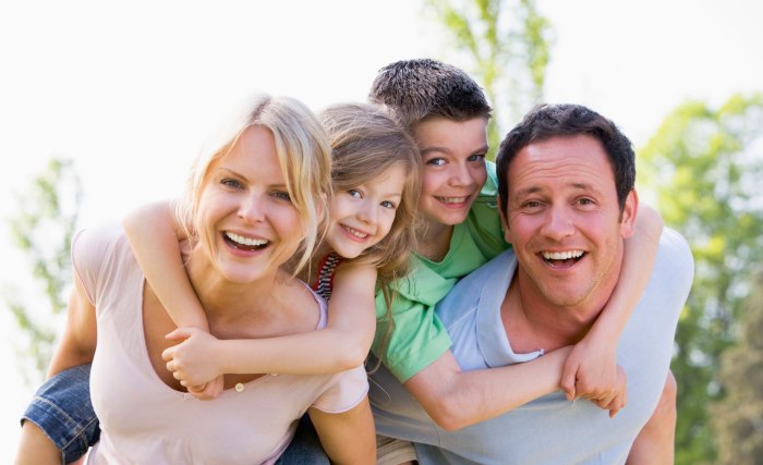 Eltern tragen zwei Kinder huckepack, lachend, © istockphoto.com©monkeybusinessimages